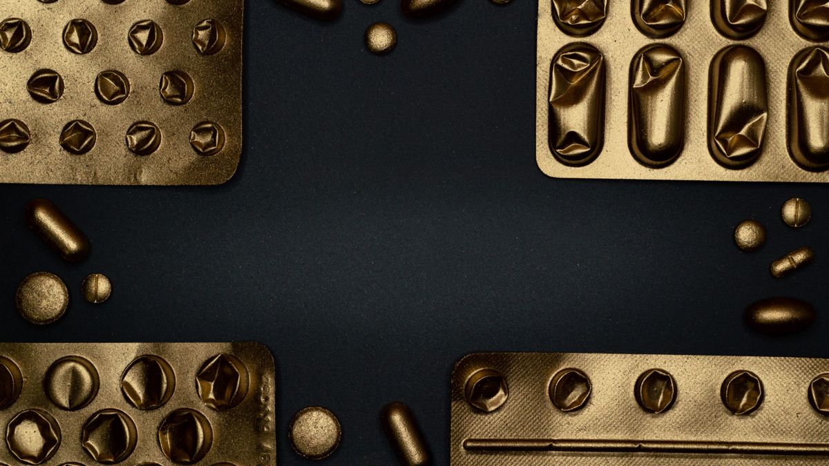 Close-up of pharmaceutical tablets beside a dried mushroom on a dark surface